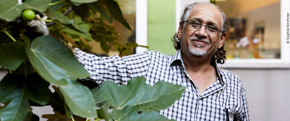 Khaled steht im Garten des Ute Bock Haus vor einem großen Feigenbaum