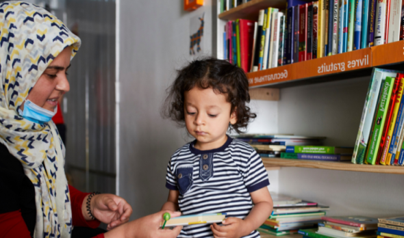 Frau mit Kind bei offenem Bücherschrank im Ute Bock Haus