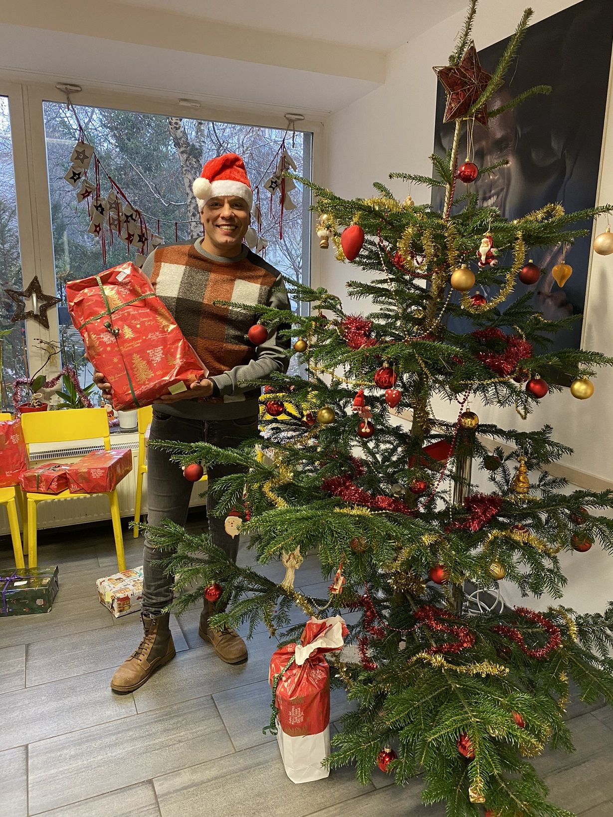 Ehrenamtlicher präsentiert Geschenke vorm Weihnachtsbaum