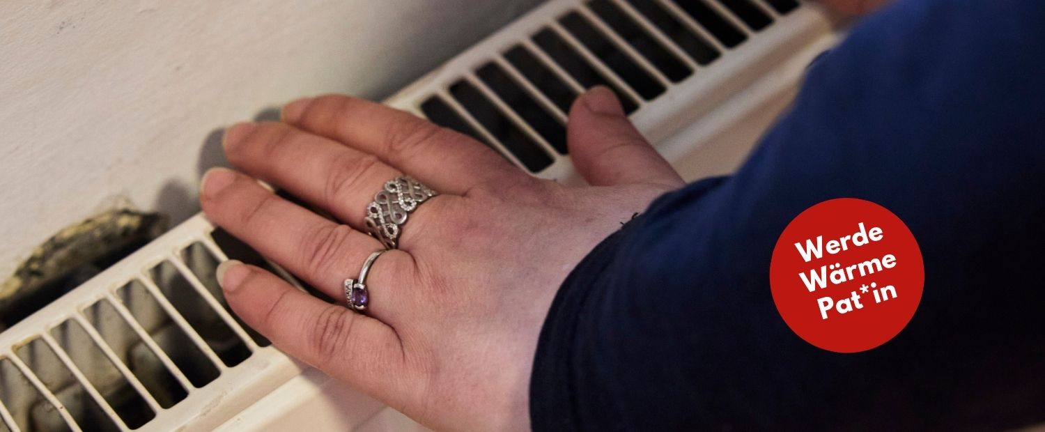 Hände mit silbernen Ringen liegen auf einem Heizkörper und wärmen sich