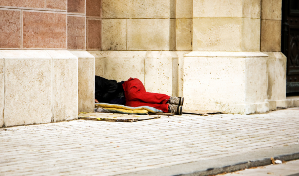 eine obdachlose Person liegt an einem Gebäude