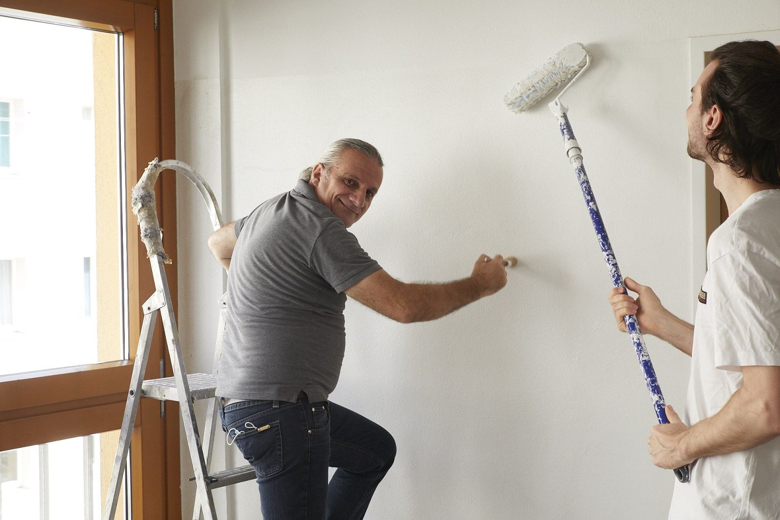 Zwei Männer streichen eine Wand