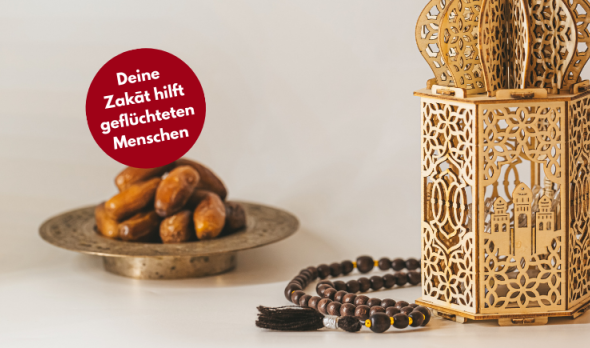 Zakāt-ul-Fitr: Ramadan-Laterne und Datteln. Davor die Bubble Dein Zakat hilft geflüchteten Menschen