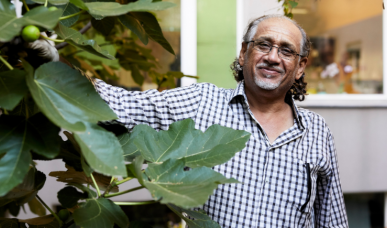 Älterer Herr steht im Garten des Ute Bock Haus bei einem großen Feigenbaum