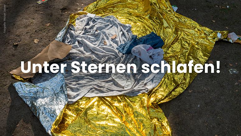 Schriftzug "Unter Sternen schlafen!" über einer Wärmedecke, die häufig bei der Flucht zum Einsatz kommt (c) Michael Danner