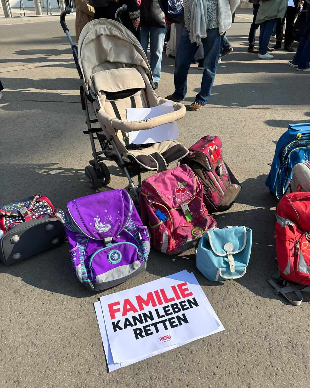 Schultaschen und leere Kinderwägen erinnern daran, dass Familienzusammenführungen Leben retten.