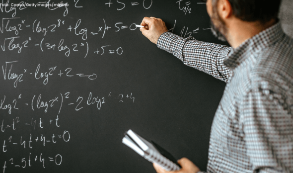 Ein Mathematiklehrer schreibt eine Formel an die Tafel.