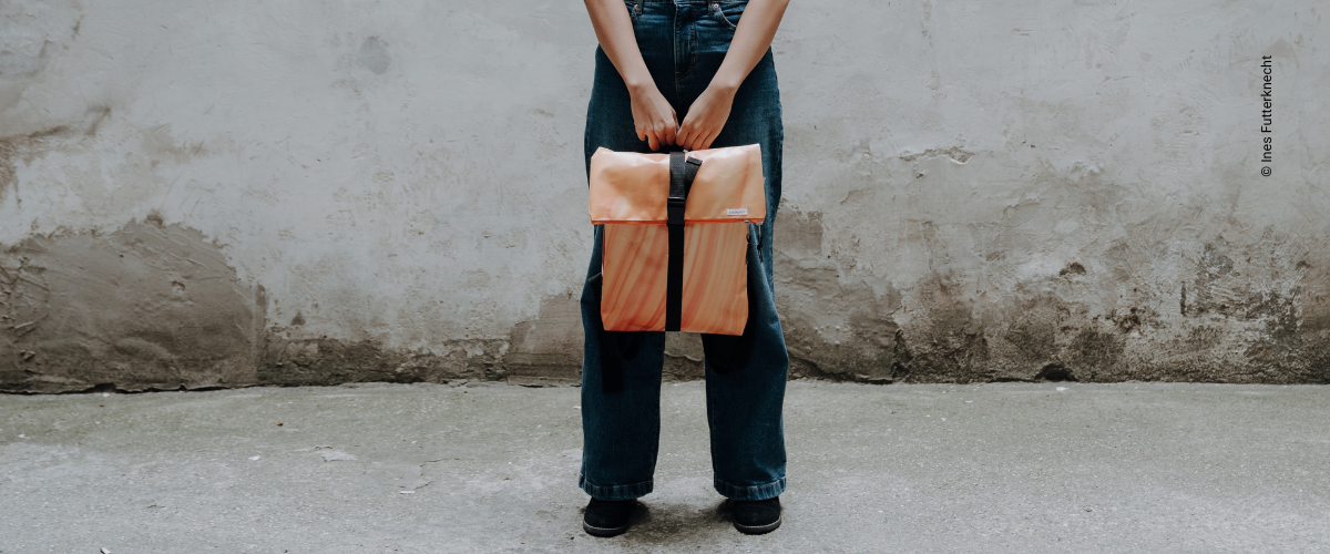Bibiane Zimba hält eines der orangen Rucksack-Unikate vom Flüchtlingspojekt Ute Bock