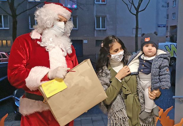 Der Weihnachtsmann übergibt einer Mutter mit Baby ein Geschenk