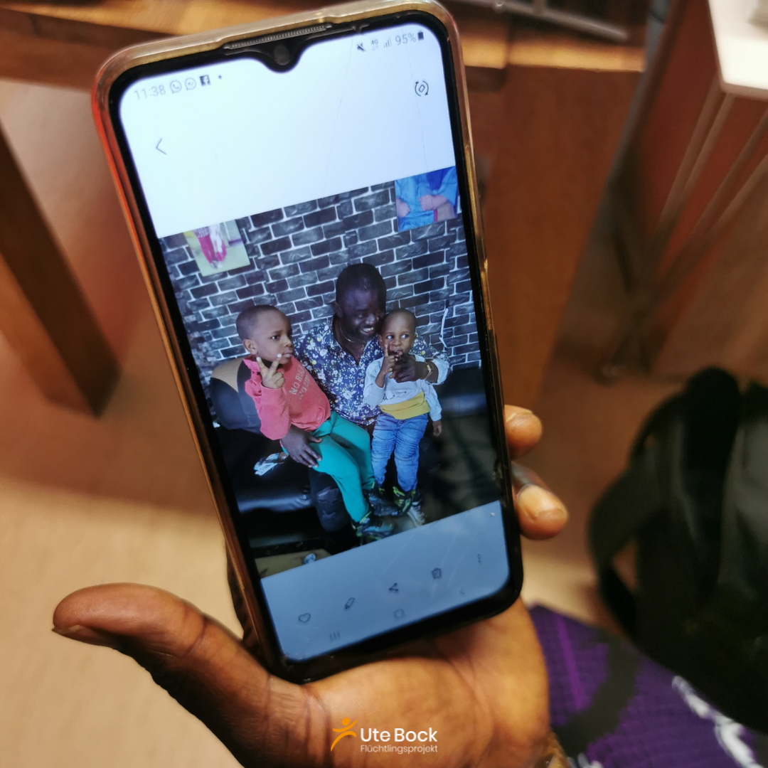 Unams zeigt stolz ein Foto von sich und seinen beiden Enkelkindern auf seinem Handy