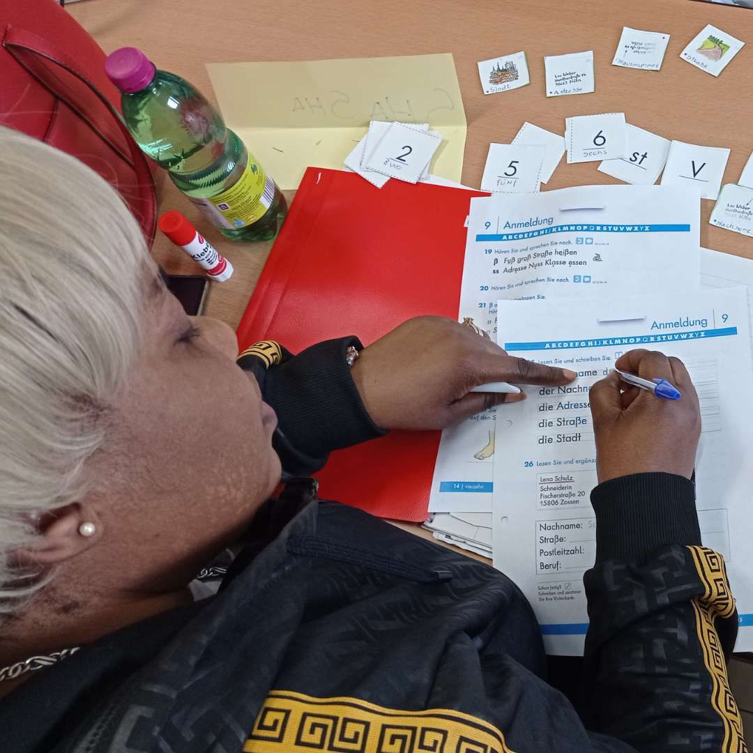 Alphabetisierungskurs Teilnehmerin nutzt Arbeitsbuch und Lernkarten