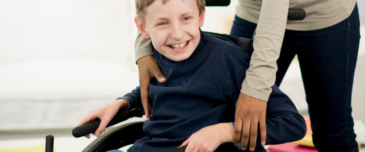 Frau hilft Kind im Rollstuhl