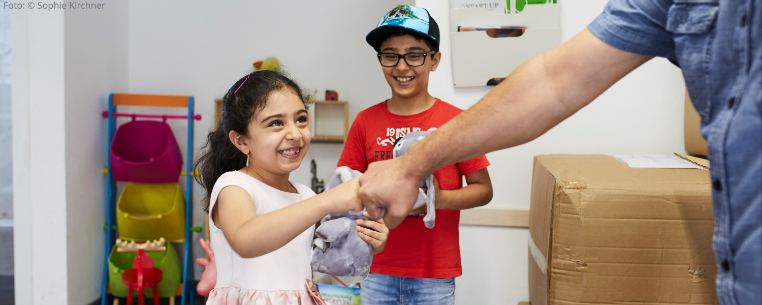 geflüchtetes Kind freut sich über gespendeten Teddy