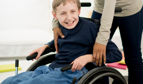 Frau hilft Kind im Rollstuhl